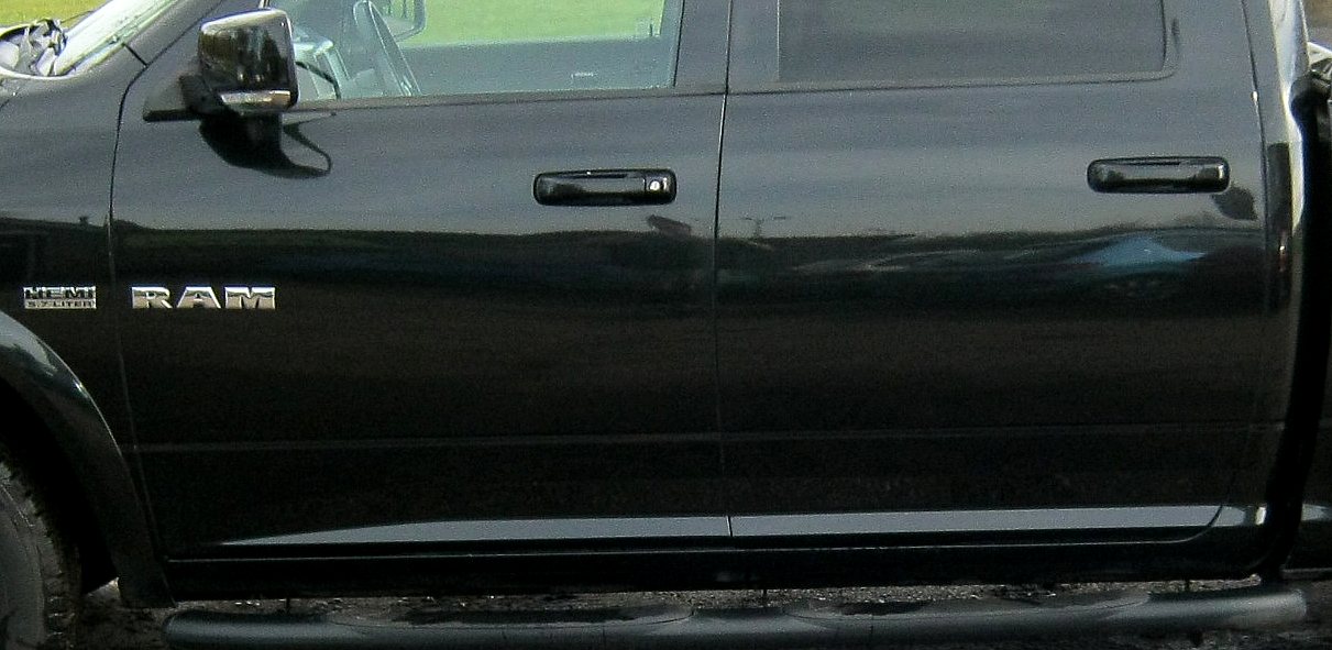 Portieren van een zwarte Dodge RAM 1500 Crew Cab met het RAM-logo en de deurgrepen