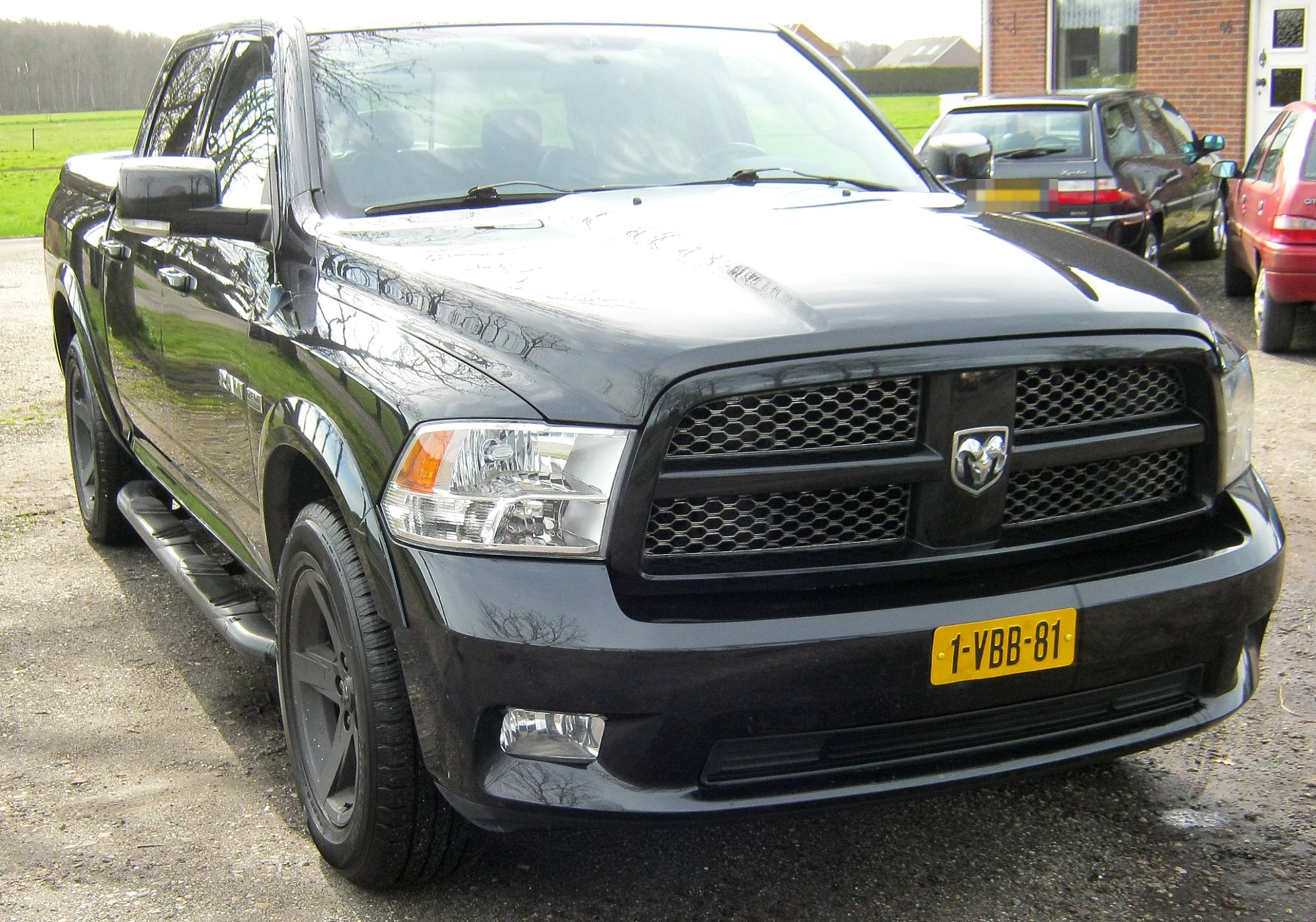Zwarte Dodge RAM 1500 Crew Cab van voren, met gele kentekenplaat, op het erf aan de Kerkweg