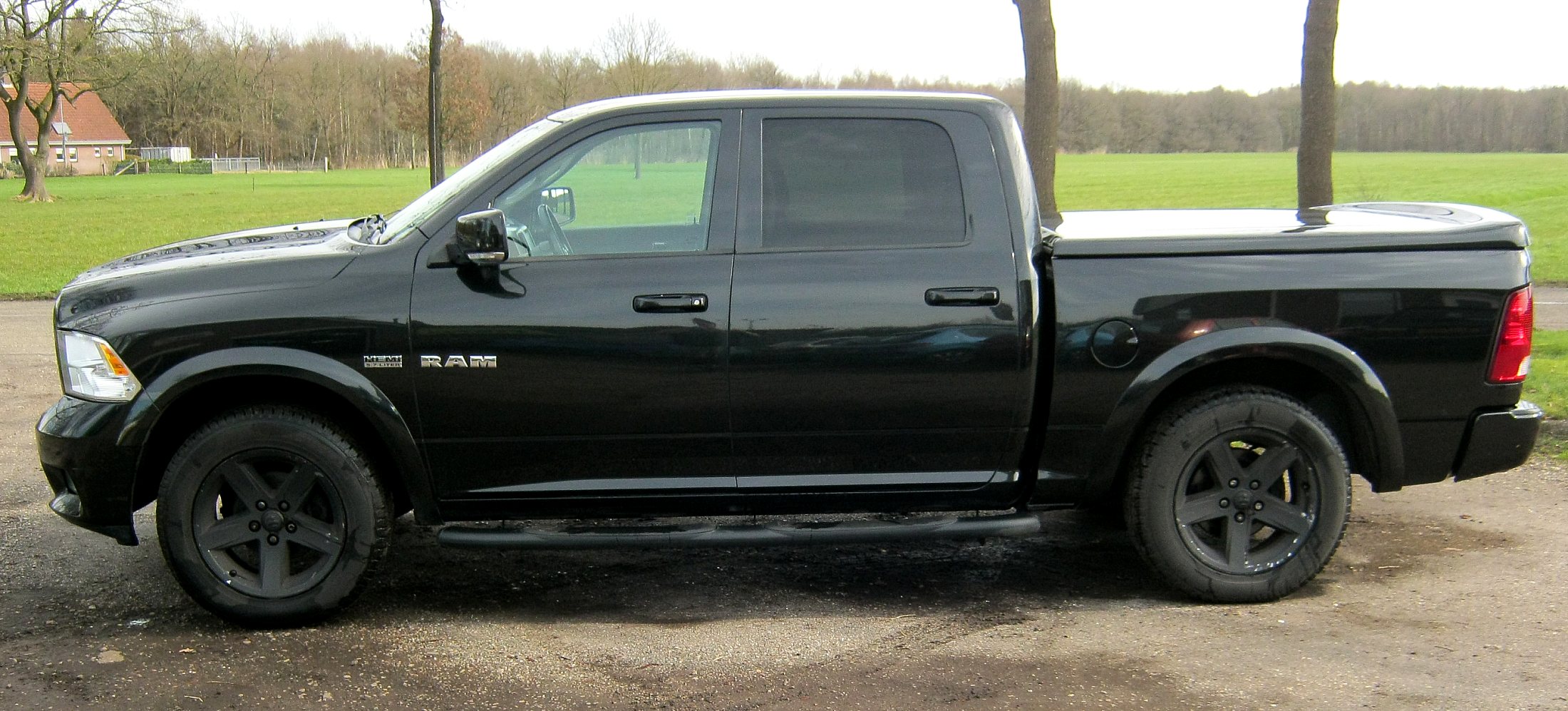 Zwarte Dodge RAM 1500 Crew Cab van de zijkant, met zwarte velgen